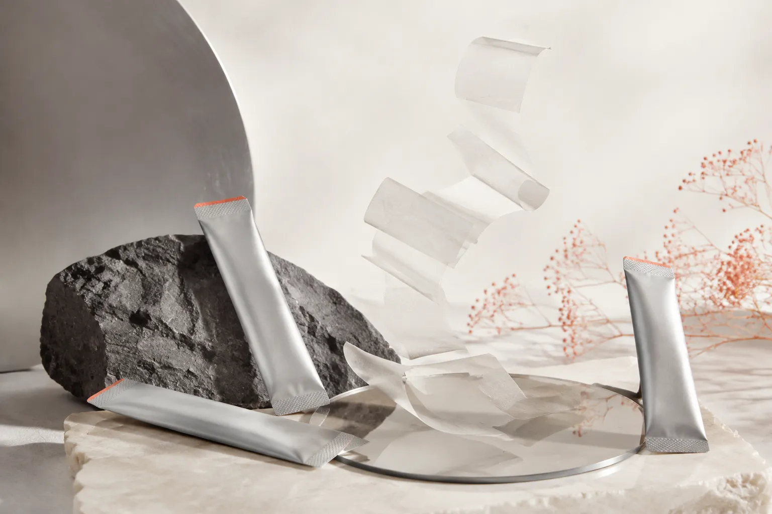 Unbranded silver individual film packs and translucent oral film sheets in a conceptual studio arrangement.