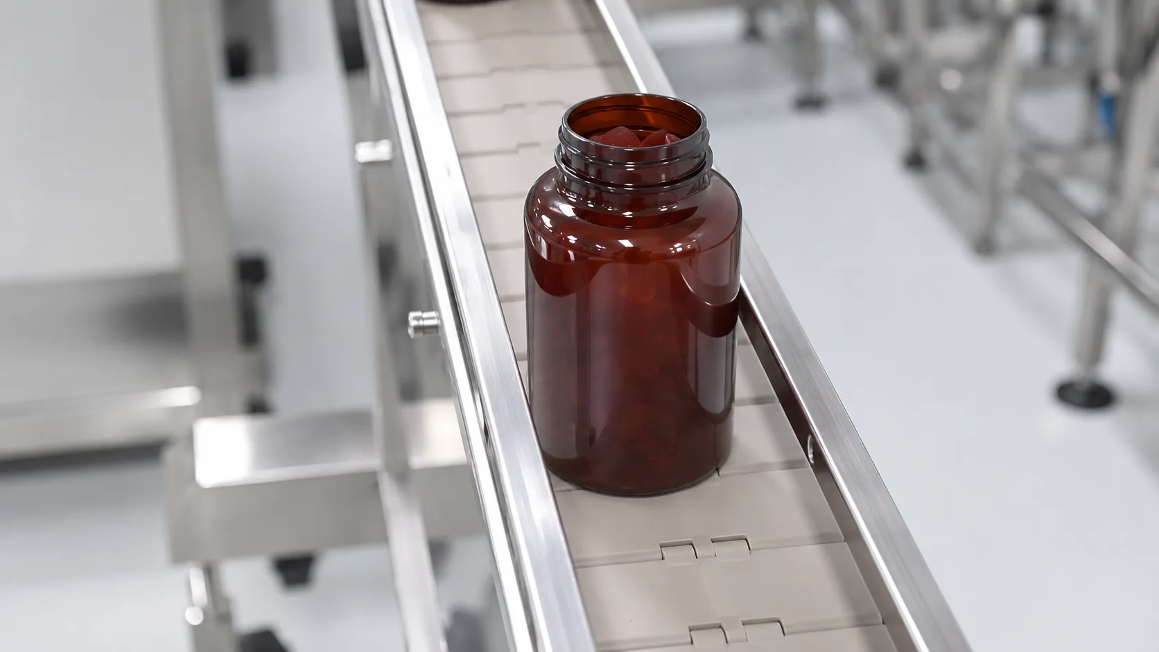 Open amber jar guided along a stainless conveyor